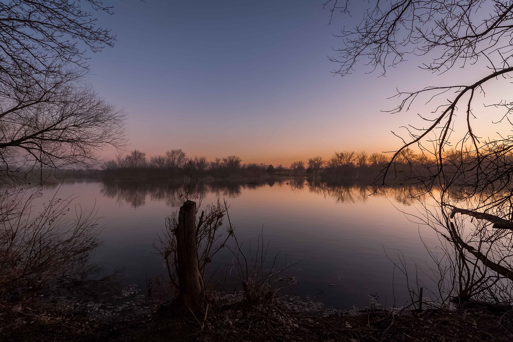 Purple and pink hues reflect on a perfectly still lake in Nebraska.