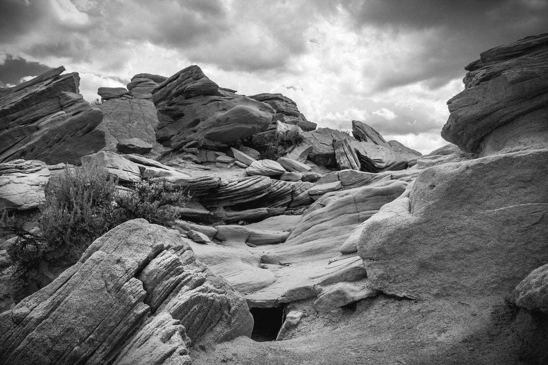 A black and white image of rocks in formation against a cloudy sky at Toadstool park in Nebraska.