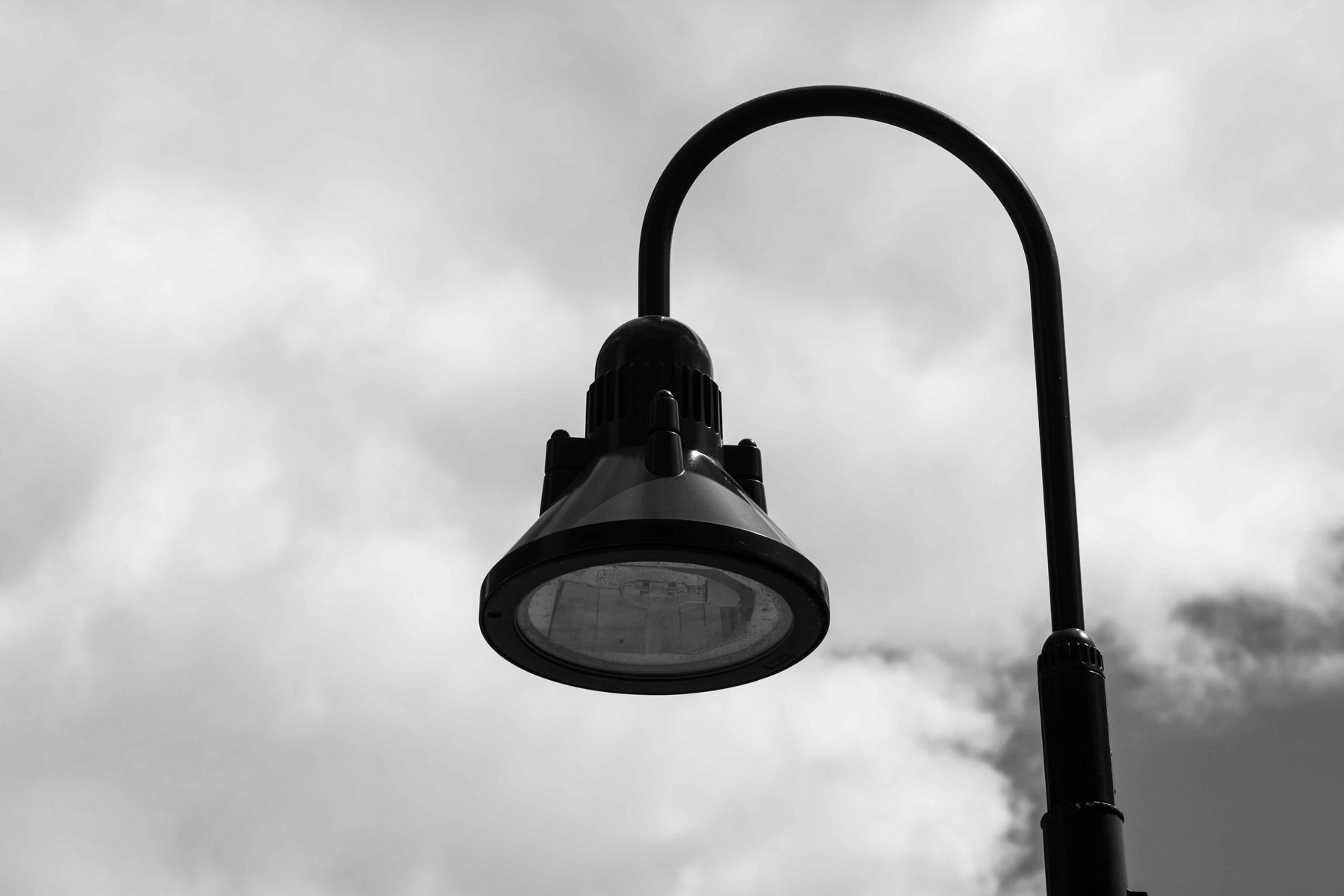 A solitary upside down U shaped lamp against a dreary grey sky.