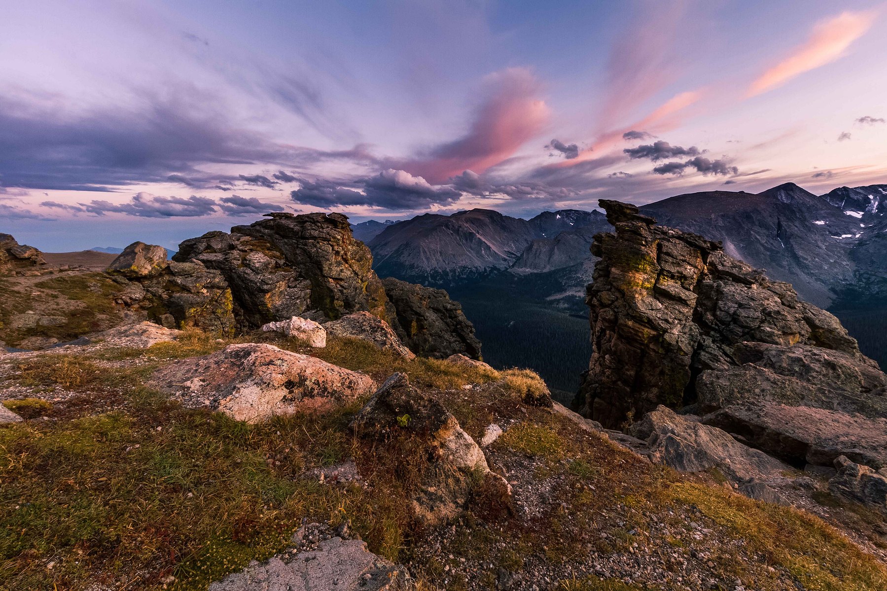 Rocks jut from the earth on a high peak overlooking a purple sunset sky.