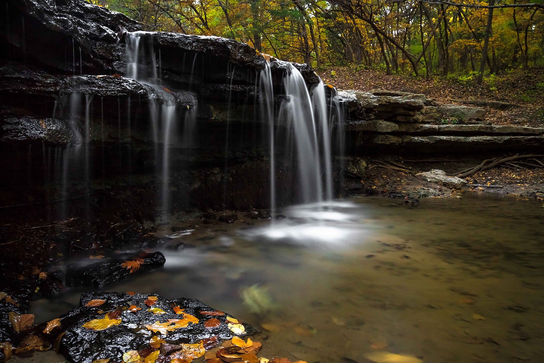 A beautiful waterfall with gorgeous autumn leaves in the foreground in Nebraska.