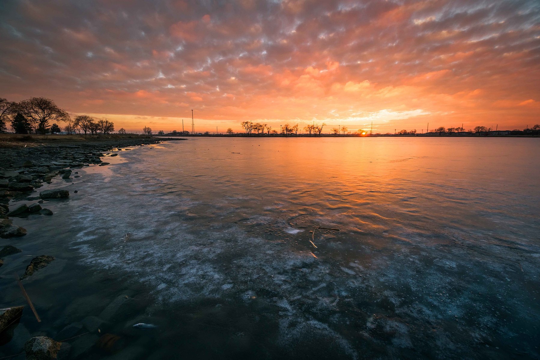 Dramatic sunset sky reflects on a frozen lake in Nebraska.