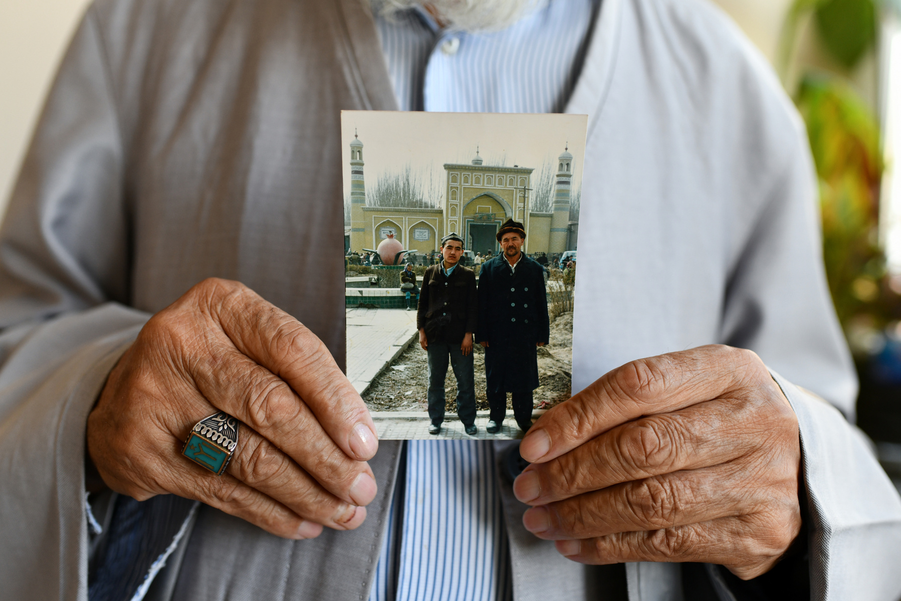 A photograph of Mahmut Tohti Amin with his eldest son Pulat Tohti, standing in front of the Id Kah Mosque in Kashgar, circa 1990.