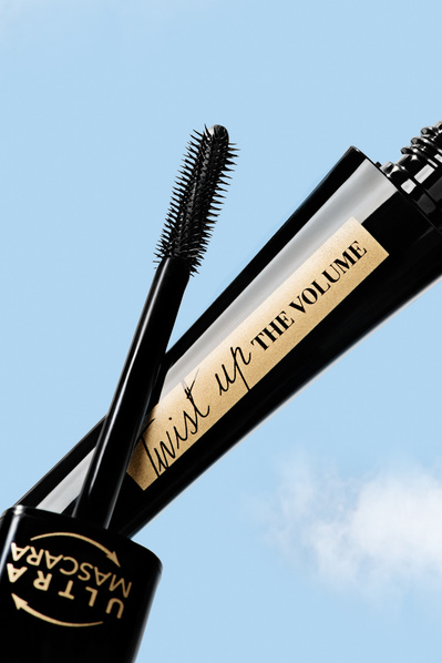 Produit cosmétique, mascara, ouvert sur fond de ciel bleu.
