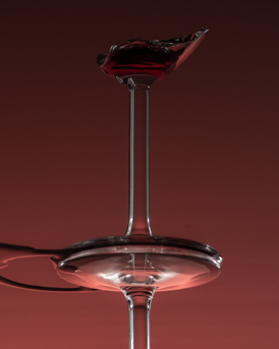 Reflet d'une coupe de vin cassée, sur fond bourgogne. 