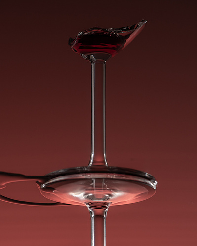 Reflet d'une coupe de vin cassée, sur fond bourgogne. 