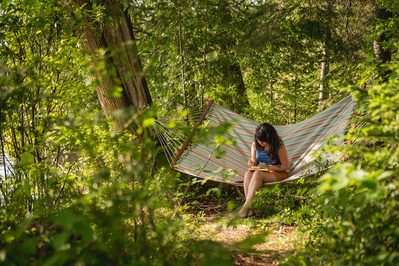 Femme dessinant dans un hamac en foret en été.