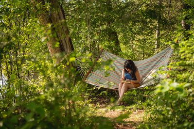 Femme dessinant dans un hamac en foret en été.