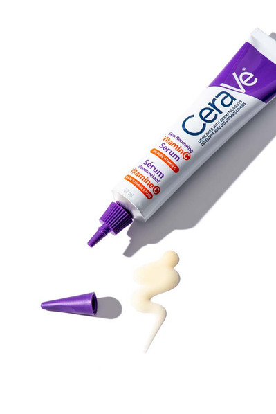 Tube de produit de beauté en crème avec bouchon violet et sa texture, sur fond blanc. 