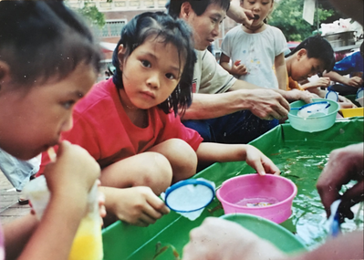 Photograph of girl scooping goldfish (tsa-bóo-gín-á khat kim-hî), Tainan, 1990s