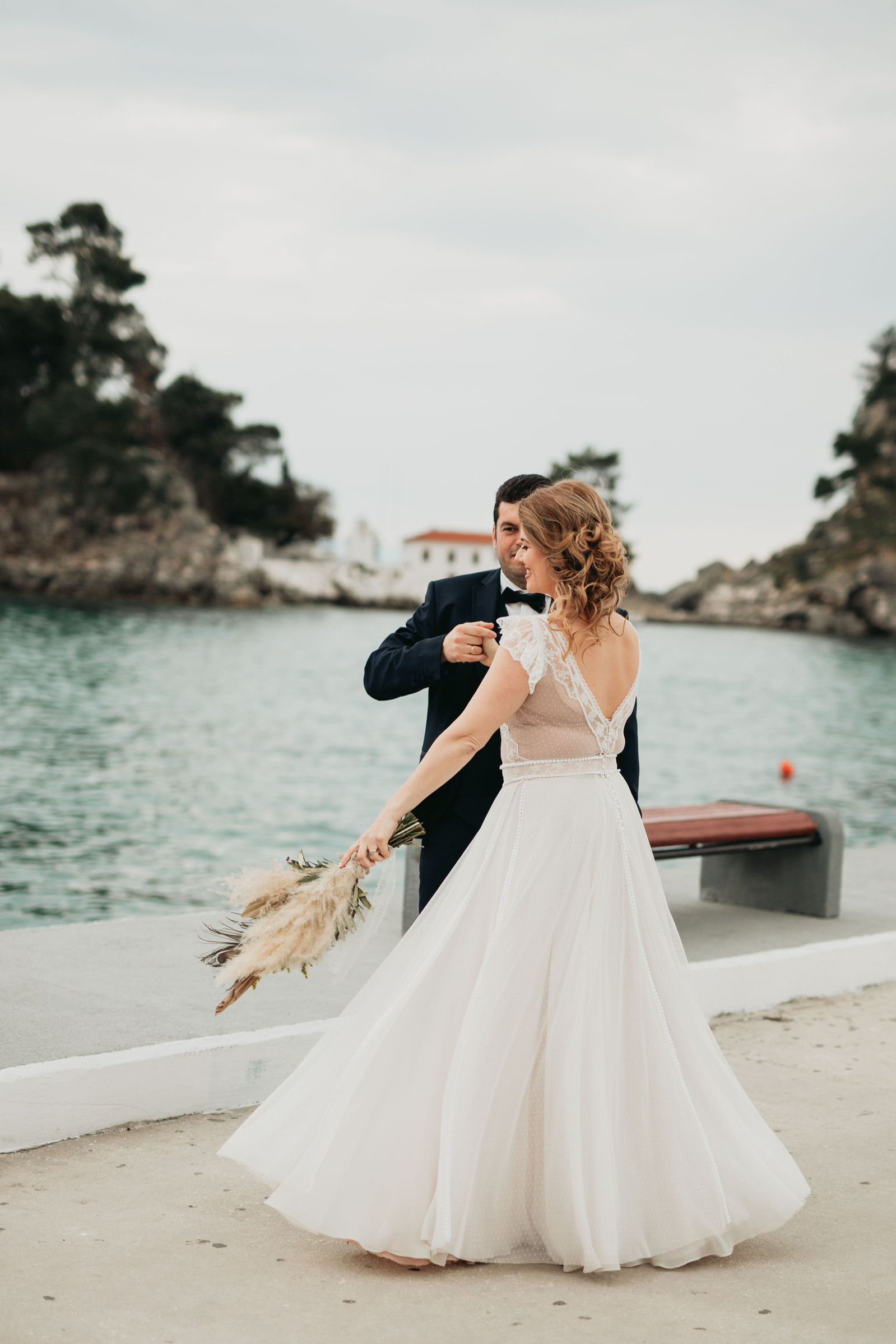 Elopement photography from Parga in Greece. A dancing couple in front of the white little church, by the water of the Ionian Sea.