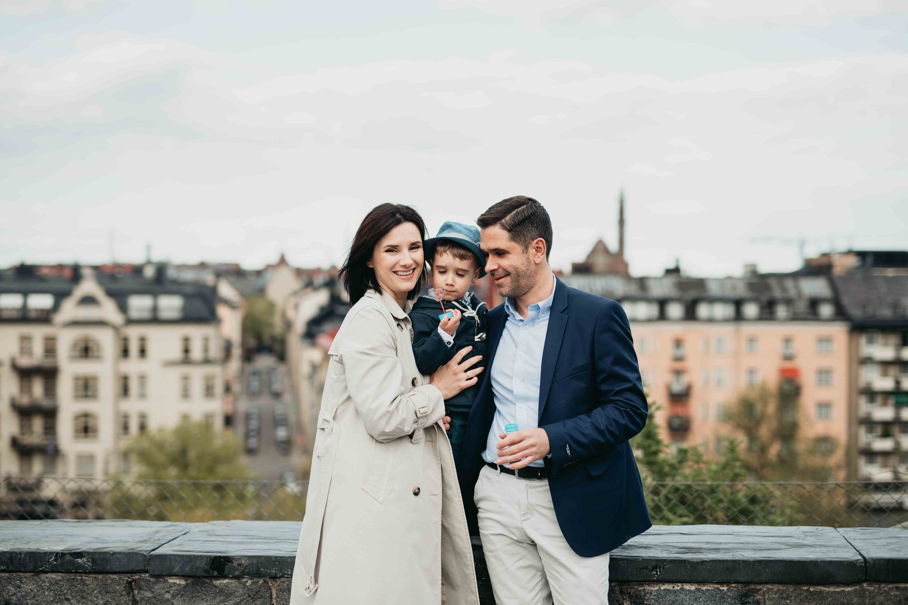 Fint familje portätt med Stockholms takåsar som bakgrund - mamma, pappa och son.