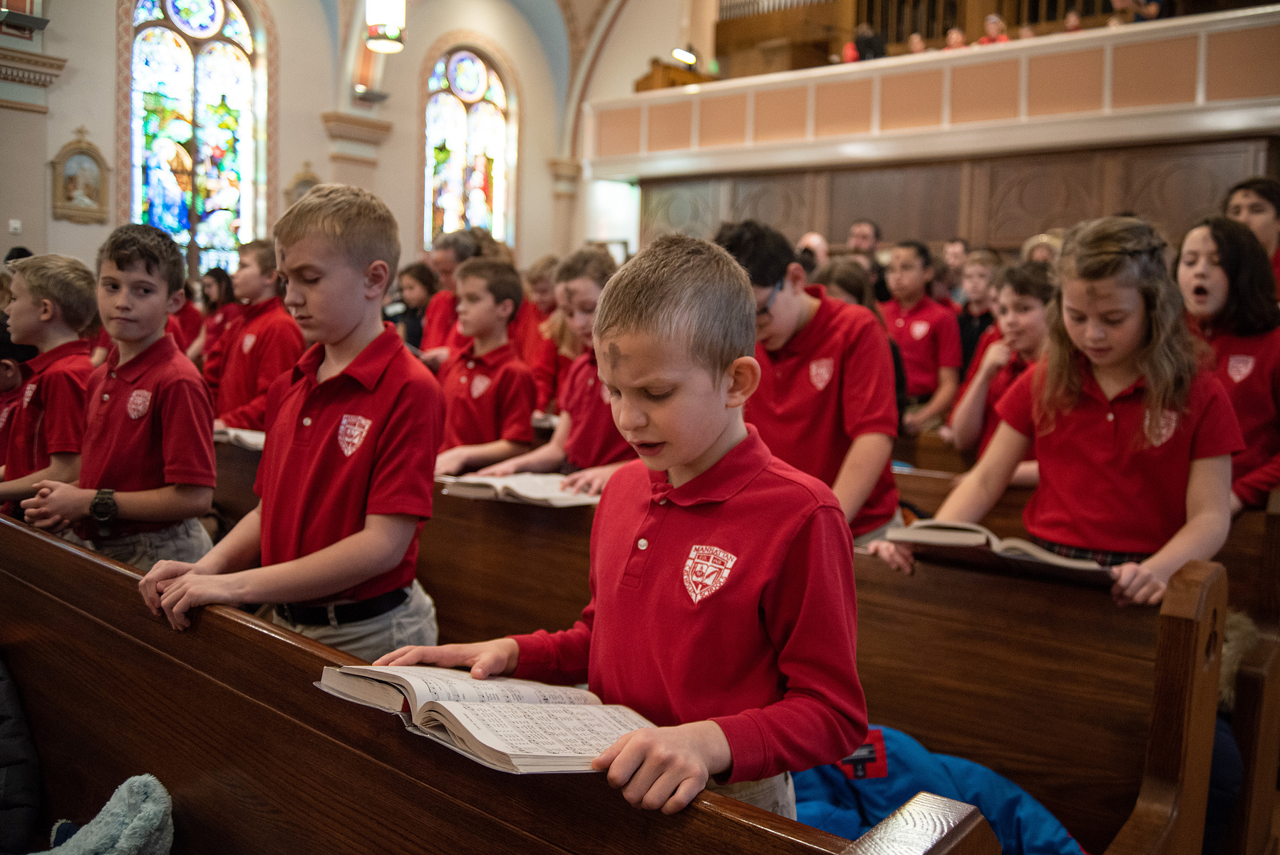 Kendall Feldkamp, a student at Manhattan Catholic School, sings with his classmates during mass at Seven Dolors Church on Ash Wednesday.
