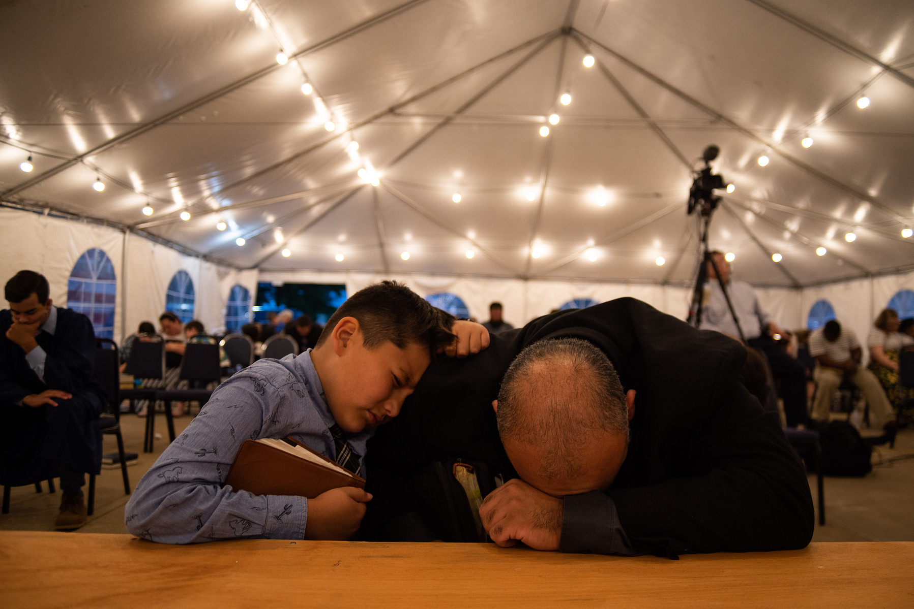 Jesse Guillen prays before the altar with his son, Easton, 10, at Harvest Baptist Church on Wedensday.