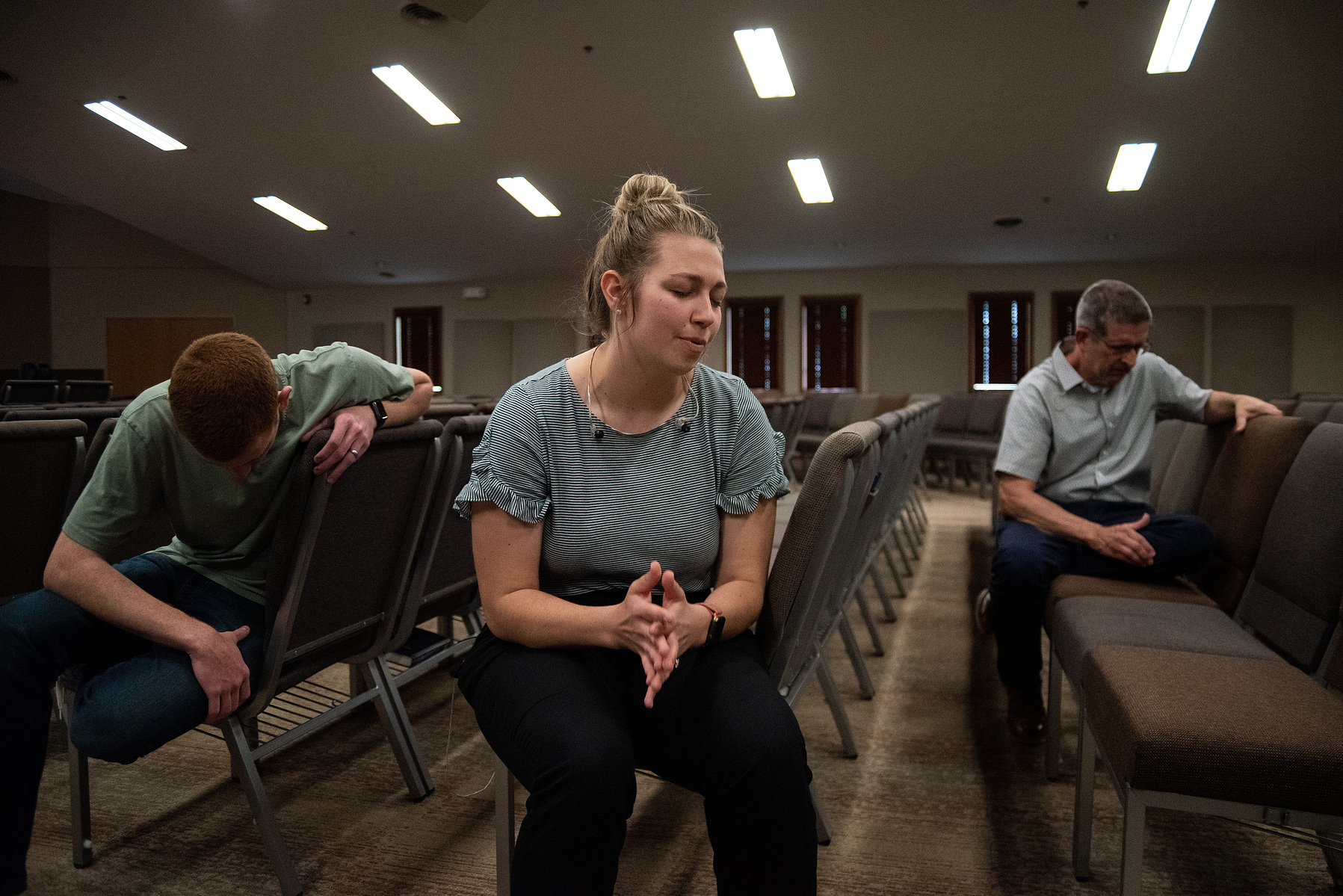 Sadie Fruth leads a prayer alongside Sam Fruth, left, and Pastor Steve Ratliff, right, before recording the service that will be streamed online for Sunday morning.