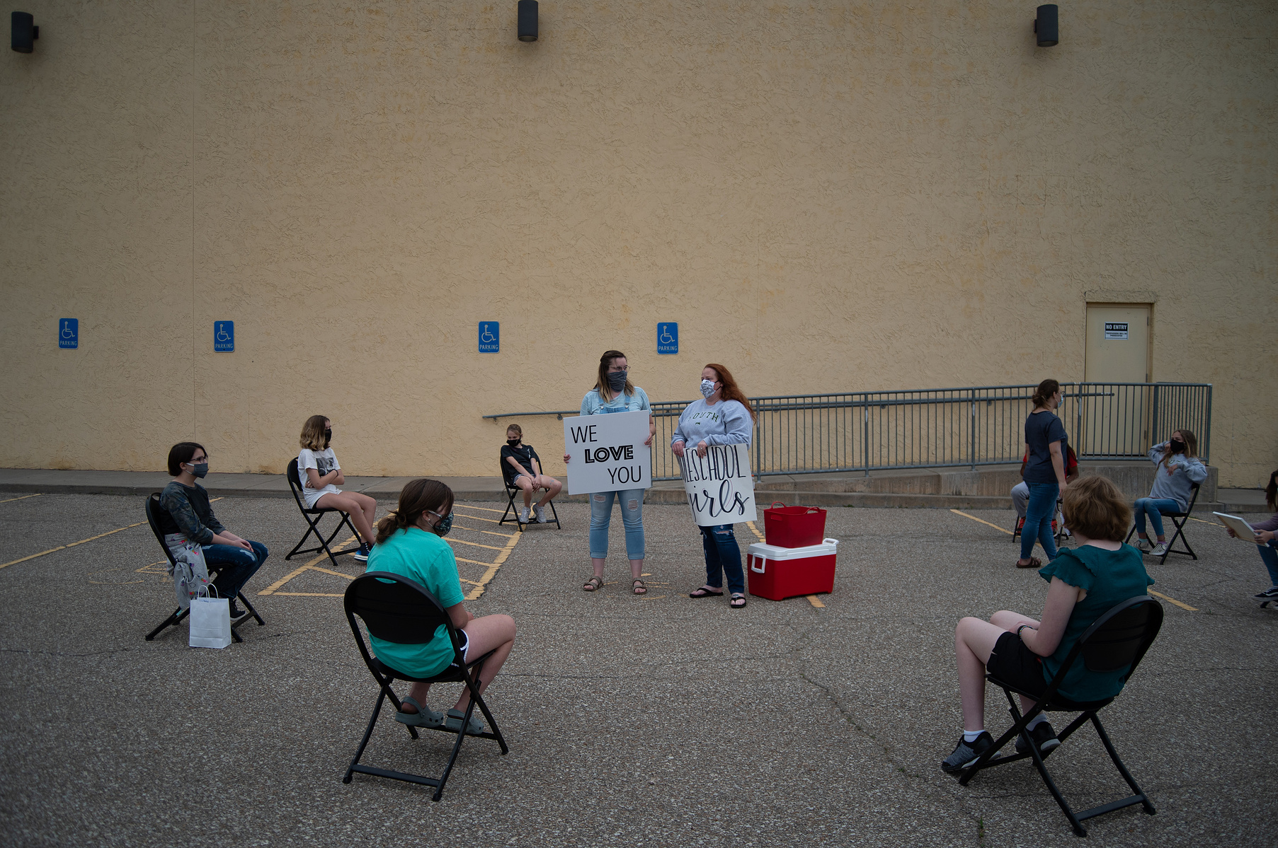 Christina Blakely, center left, and Sarah Martin, center right, wait for more of their youth group members to show up to their social distancing hangout outside of Rock Hills Church on Wednesday.