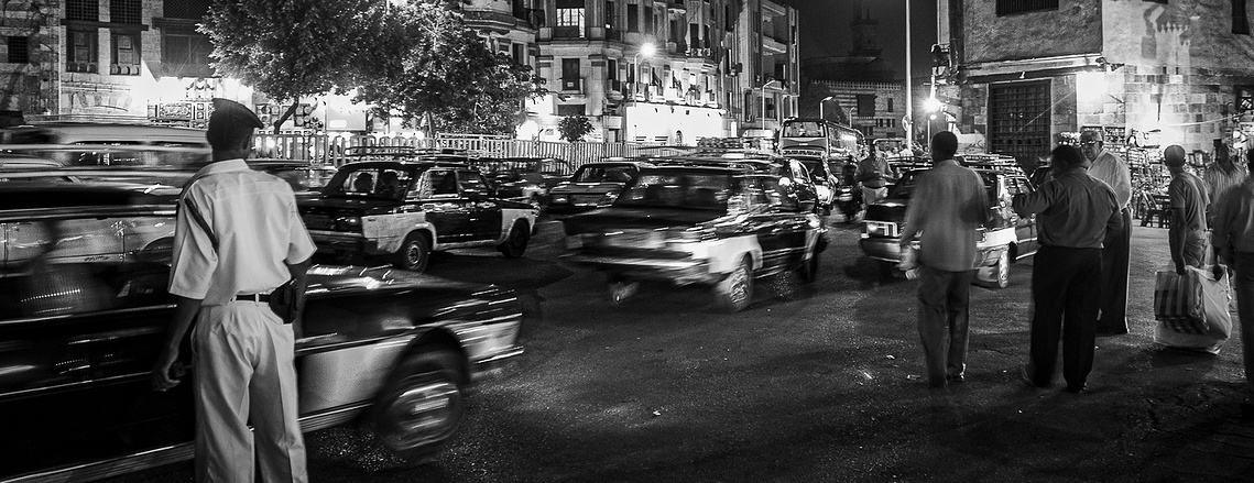 Evening streets come alive with motion and light in this stunning black-and-white capture. Learn how to create compelling urban stories with long exposure and composition in our professional photography courses.