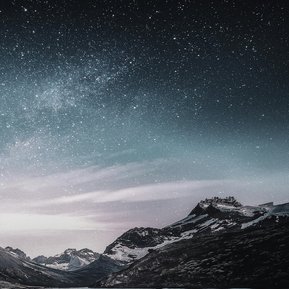 Au premier plan des flots bleus et blancs, mousseux d'écume, nous ménent à une chaîne de montagnes partiellement enneigés, le tout illuminé par un ciel étoilé. 