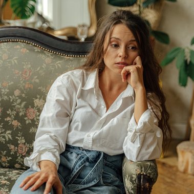 Jeune femme pensive assise sur un divan durant une séance de Gestalt-thérapie individuelle