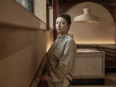 Vermeer like portrait of producer Thea Gajic in a warm toned restaurant.