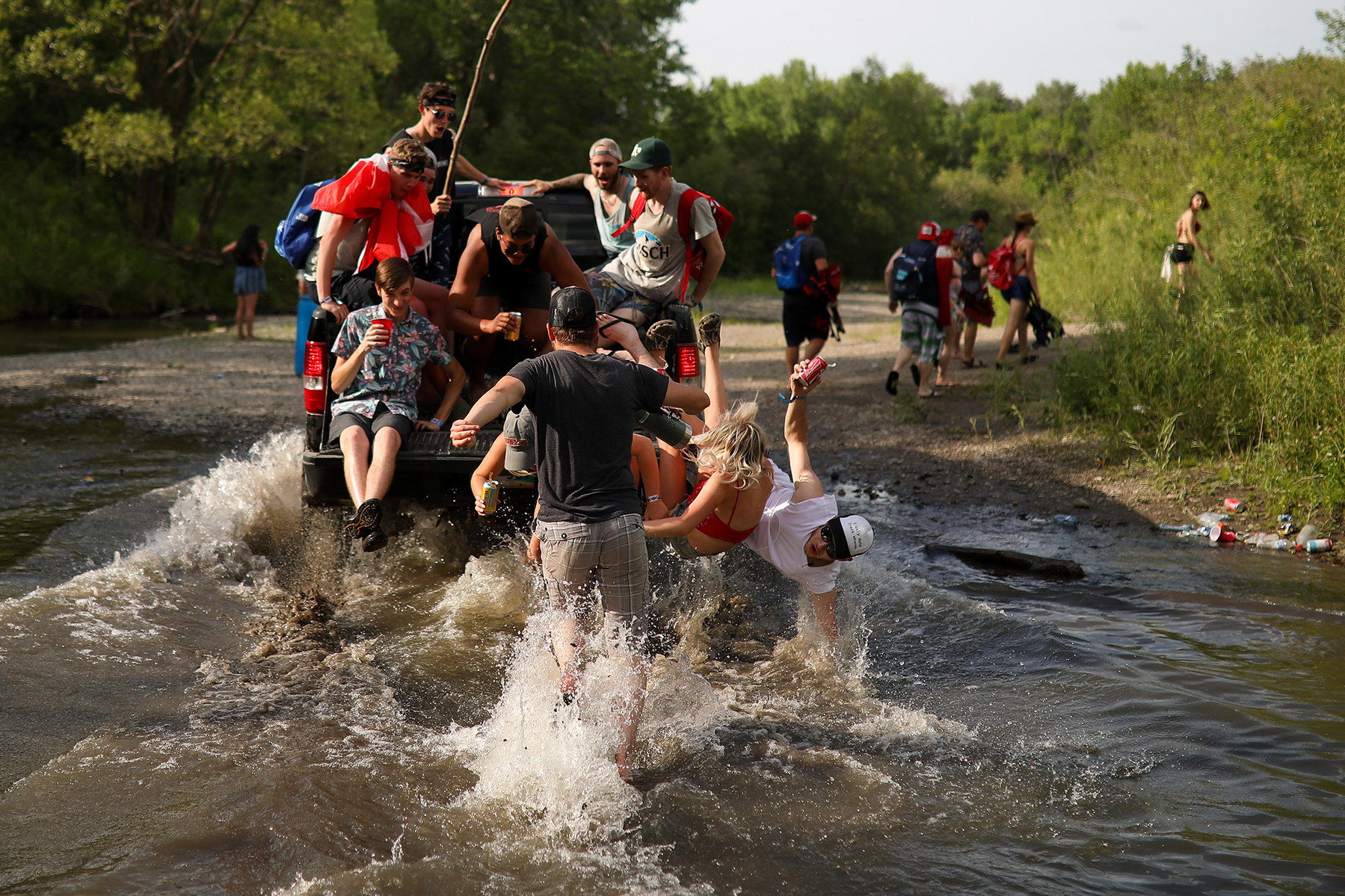 Young men and women fall from a moving pickup truck as it crosses a creek during the Dauphin's Countryfest music festival.