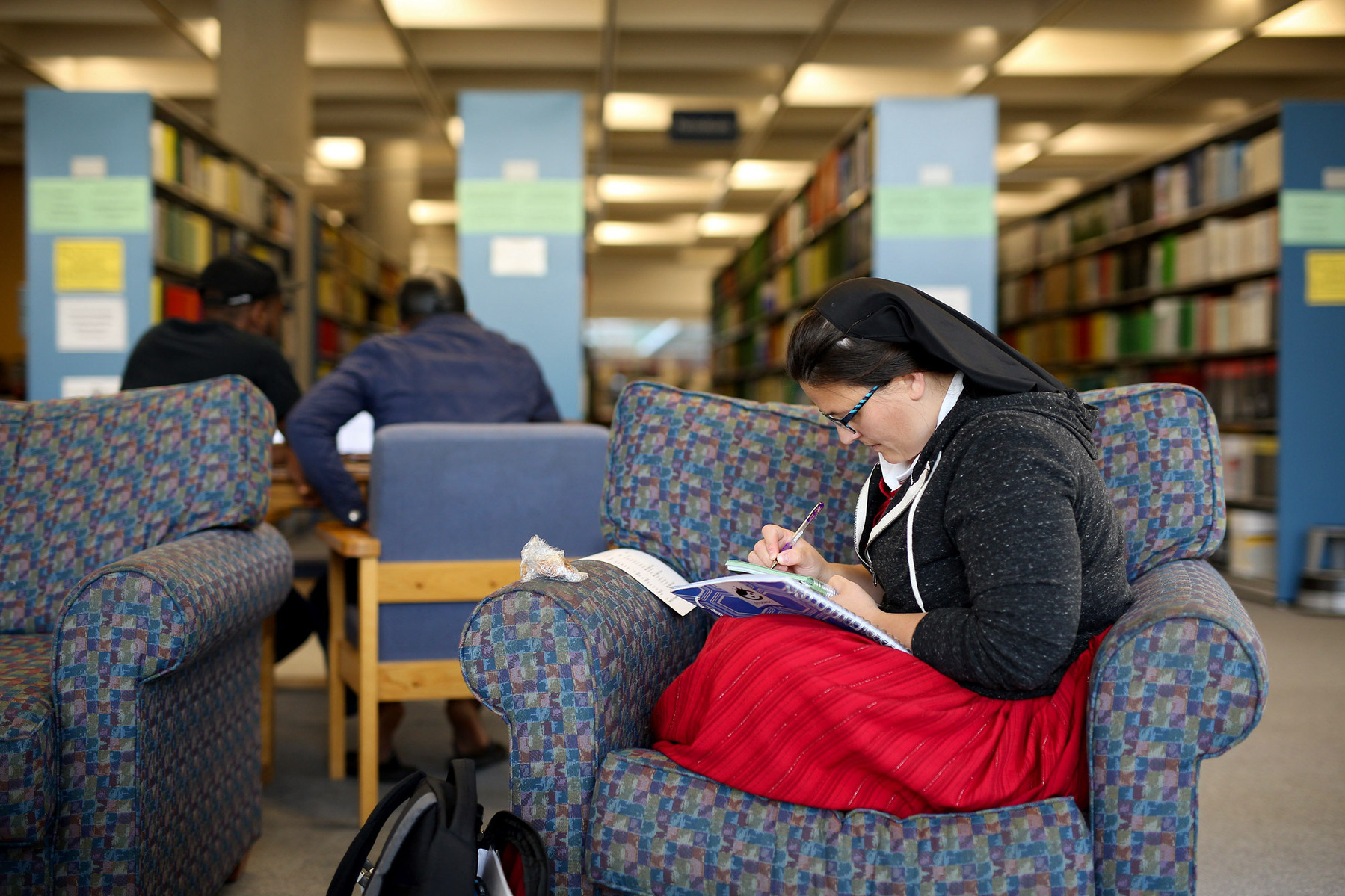 A Hutterite woman studies in the library of Brandon University.
