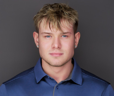 Corporate headshot of a young man with short blonde hair, wearing a blue polo against a neutral gray background. Ideal for LinkedIn profiles, personal branding, corporate headshots, and professional networking in Arlington Heights and Chicago.