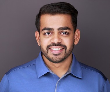 Corporate headshot of a man with short dark hair and a well-groomed beard, wearing a blue polo against a neutral gray background. Ideal for LinkedIn profiles, corporate branding, and professional networking in Arlington Heights and Chicago.