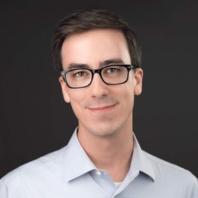 Polished headshot of a man with dark hair and glasses, wearing a light blue collared shirt against a dark backdrop. Ideal for LinkedIn profiles, corporate branding, and actor headshots in Arlington Heights and Chicago.