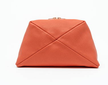 Handcrafted coral leather cosmetic bag with a unique geometric design. The Stella toiletry bag, made in Delft, Netherlands, features premium textured leather and a rose gold zip. Perfect for storing beauty essentials at home or on the go