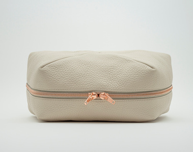 Handcrafted beige leather cosmetic bag with a unique geometric design. The Stella toiletry bag, made in Delft, Netherlands, features premium textured leather and a rose gold zip. Perfect for storing beauty essentials at home or on the go