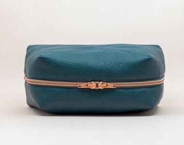 Handcrafted leather cosmetic bag with a unique geometric design. The Stella toiletry bag, made in Delft, Netherlands, features premium pebble grain leather and a rose gold zip. Made to order. Colour: petrol blue