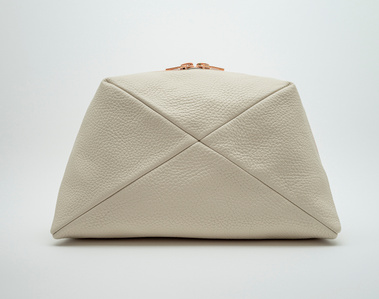 Handcrafted beige leather cosmetic bag with a unique geometric design. The Stella toiletry bag, made in Delft, Netherlands, features premium textured leather and a rose gold zip. Perfect for storing beauty essentials at home or on the go