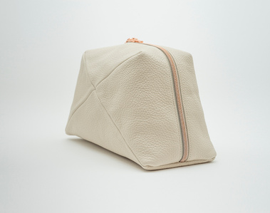 Handcrafted beige leather cosmetic bag with a unique geometric design. The Stella cosmetic bag, made in Delft, Netherlands, features premium textured leather and a rose gold zip. Perfect for storing beauty essentials at home or on the go