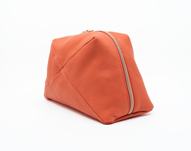 Handcrafted coral leather cosmetic bag with a unique geometric design. The Stella toiletry bag, made in Delft, Netherlands, features premium textured leather and a rose gold zip. Available in a made-to-order small-batch production