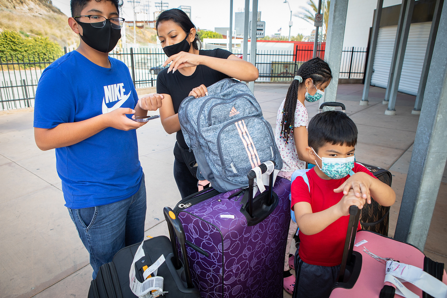 Michelle Arenas waits with her three children for a shuttle bus to Las Vegas at the San Ysidro Transit Center, June 6, 2020. The family began their day of travel in Michoacán, where they were attending a wedding.