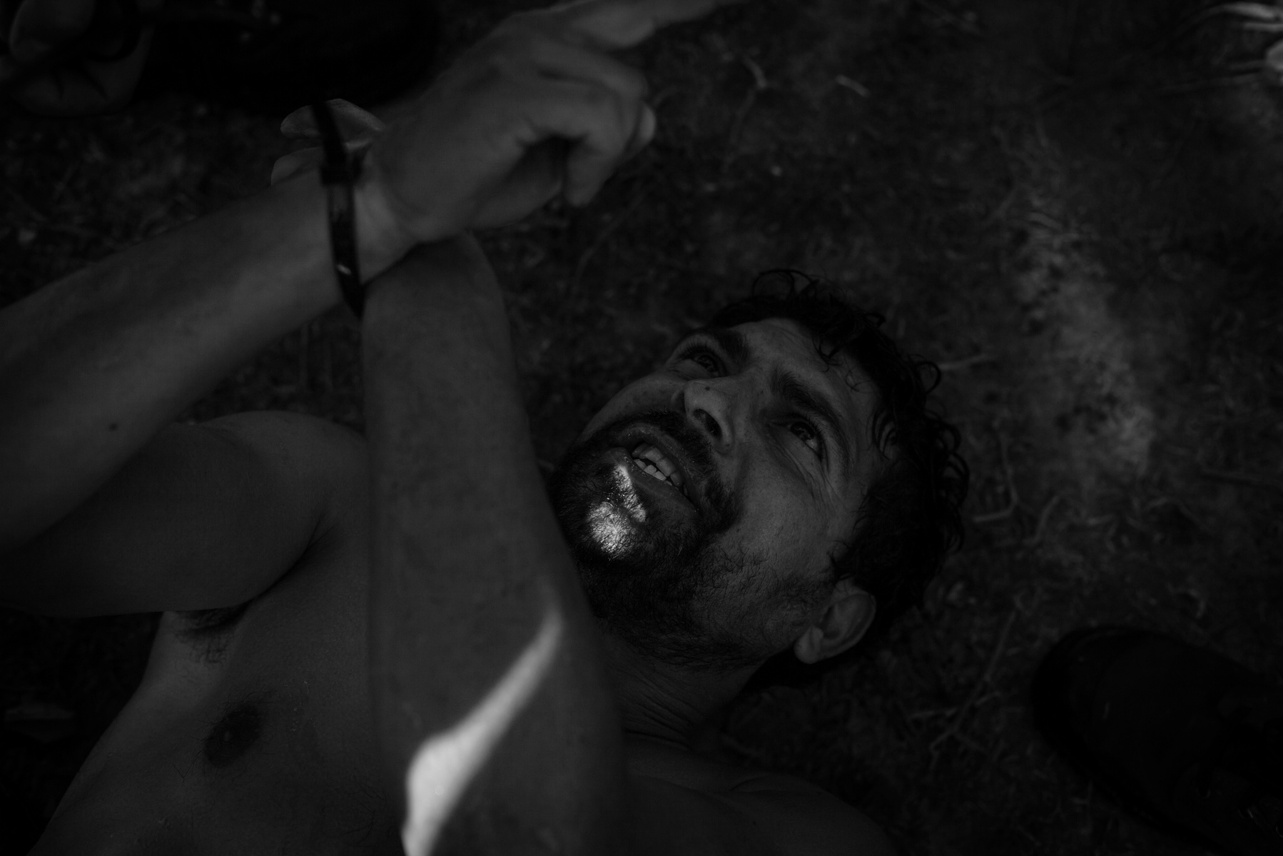 A captured Turkish smuggler is restrained on the ground by volunteer helpers. Coming by boat with refugees on Pharos beach with in mind to bring back the boat to Turkey, he then unsuccessfully evaded attempts by people to capture him. He ran to the sea wh