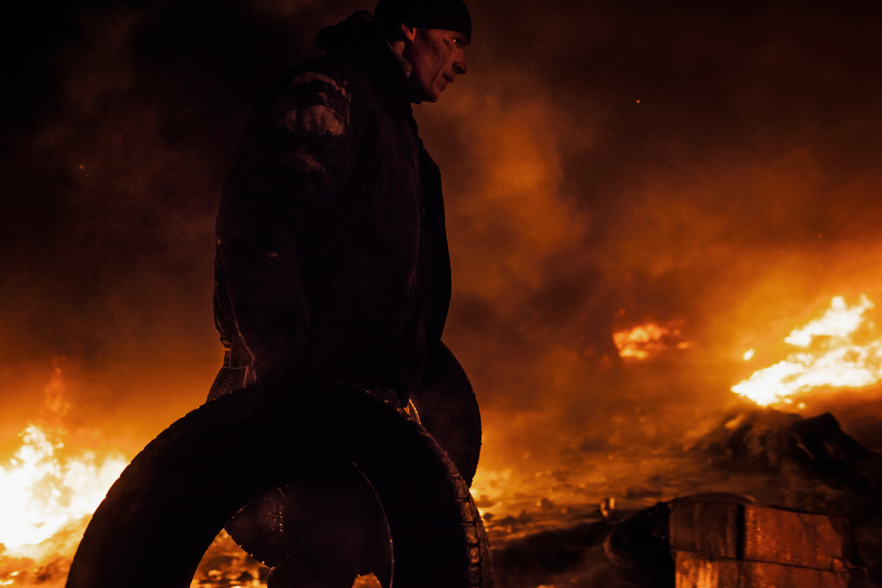 Protesters feed a fire barricade with tires during clashes between anti-government protesters and riot police on Hrushevskoho street in Kiev. 24 January 2014