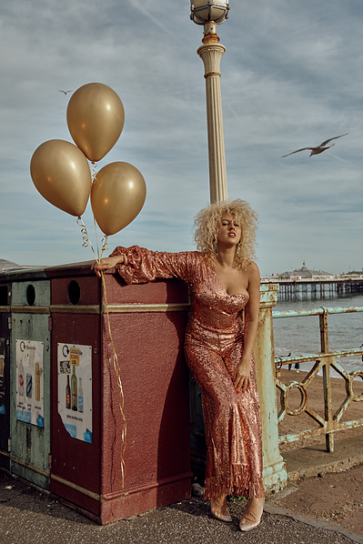 Sydney Jo Jackson with Bryan Michael Ham Photography in Brighton Beach U.K. Gold Balloons, Shiny pant suit and walking the boardwalk.
