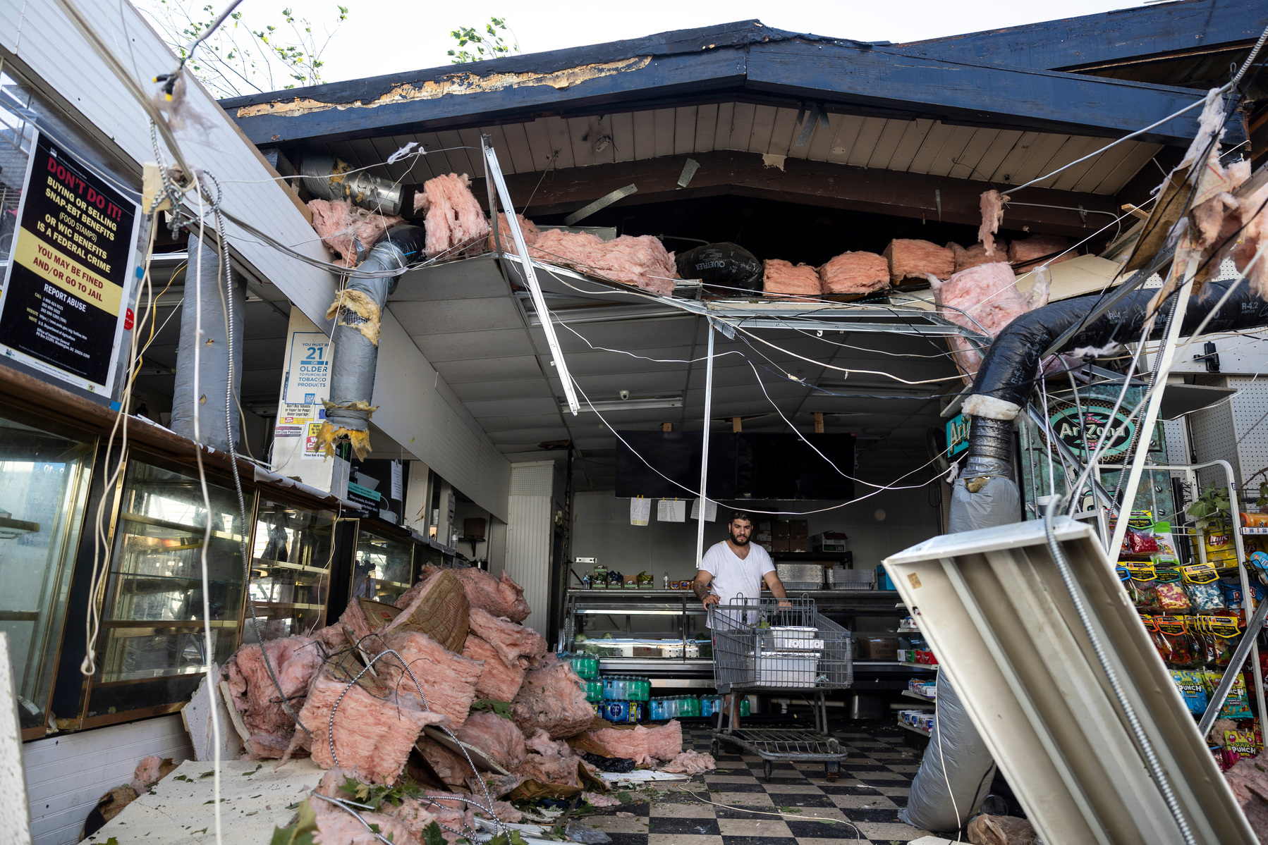 Zuhdija Omerovic carts fish out of Pops Kingshighway Market while it's still fresh after the roof was ripped off by a tornado that hit around Fountain Park in St. Louis on May 16, 2025.
