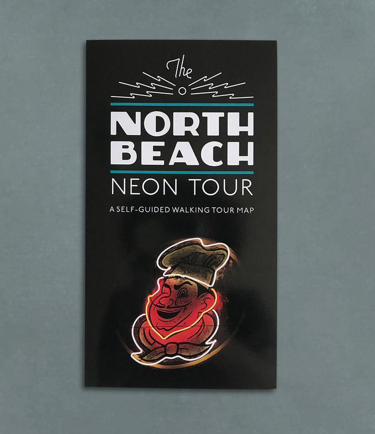 Cover of the North Beach neon tour folded map with a vintage neon sign of a man's smiling face, and wearing a chef's hat and tie.