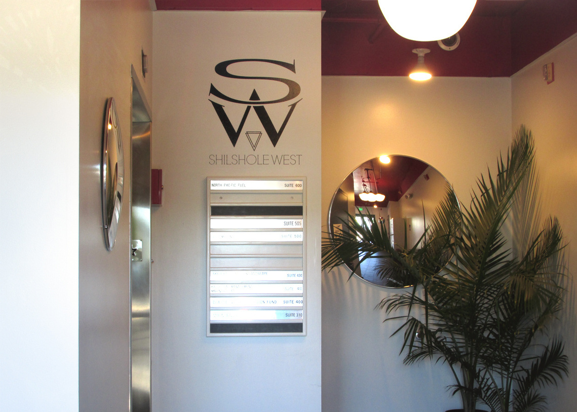 Lobby of the Shilshole West building featuring the SW logo, directory, a mirror, and a potted palm tree by the elevator.