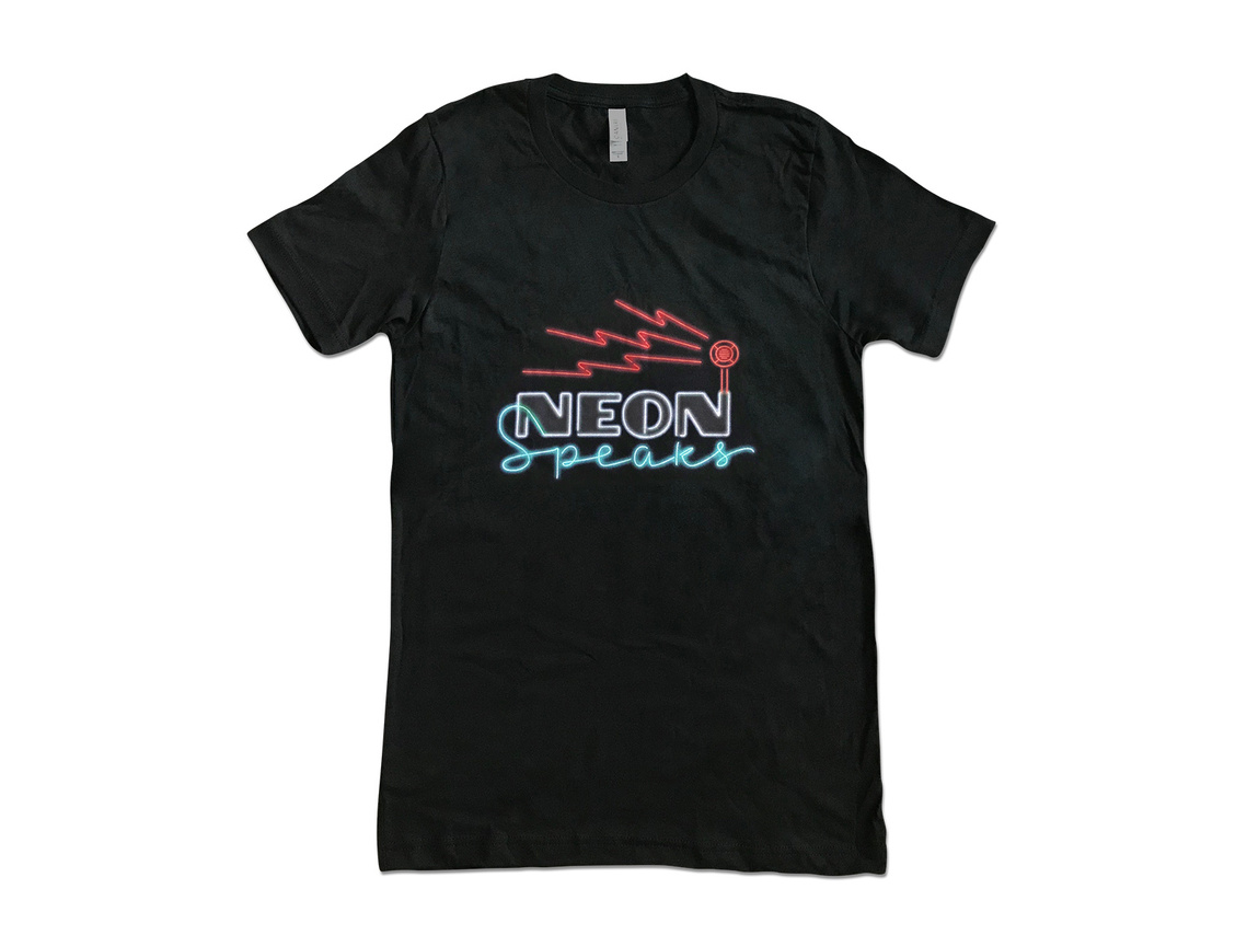 Tshirt featuring the logo for the Neon Speaks festival and symposium, with a mix of art deco capital letters, an neon tube style upright script, with a round vintage style speaker and lightning bolt shaped neon sound waves emitting from the speaker.