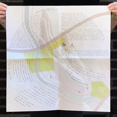 The "Above/Inside" poster unfolded and held up by 2 hands, featuring poetry overlaid on a map of Redmond Washington's system of waterways and parks.