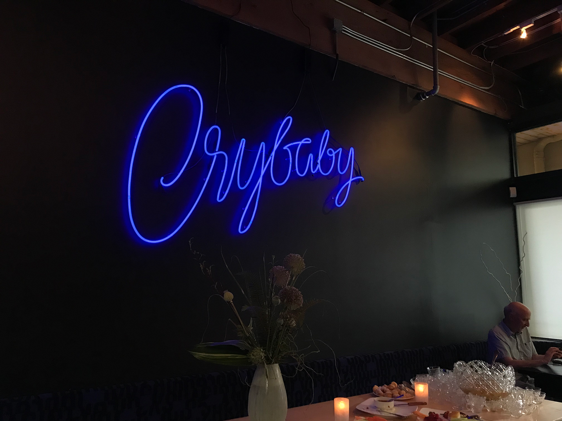 A lit neon sign, designed with expressive blue script lettering, spelling out the word 