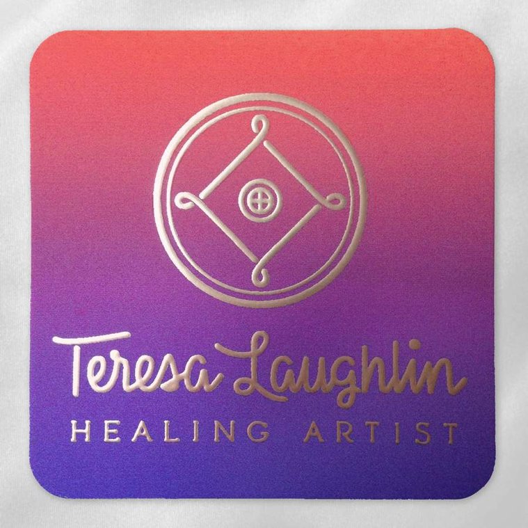 Business card of the logo design for Teresa Laughlin, Healing Artist, in gold ink, with custom lettering in an upright script, a shield knot icon with a medicine wheel at its center, and a vibrant sunset-like gradient of purple and orange.