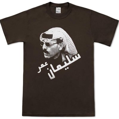 Dark brown Omar Souleyman t-shirt with a 3/4 portrait of Omar Souleyman wearing sunglasses and keffiyeh, with his name written in Arabic at an angle below.
