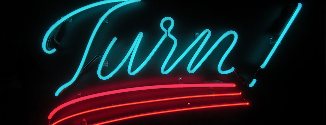Portion of a neon sign with blue, pink, and red tubes.