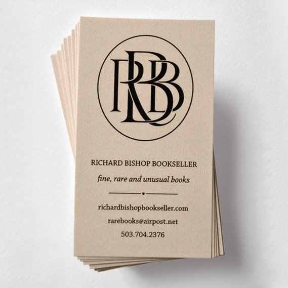 A stack of business cards for Richard Bishop bookseller. The cards are tan with black text as well as a monogram design of 