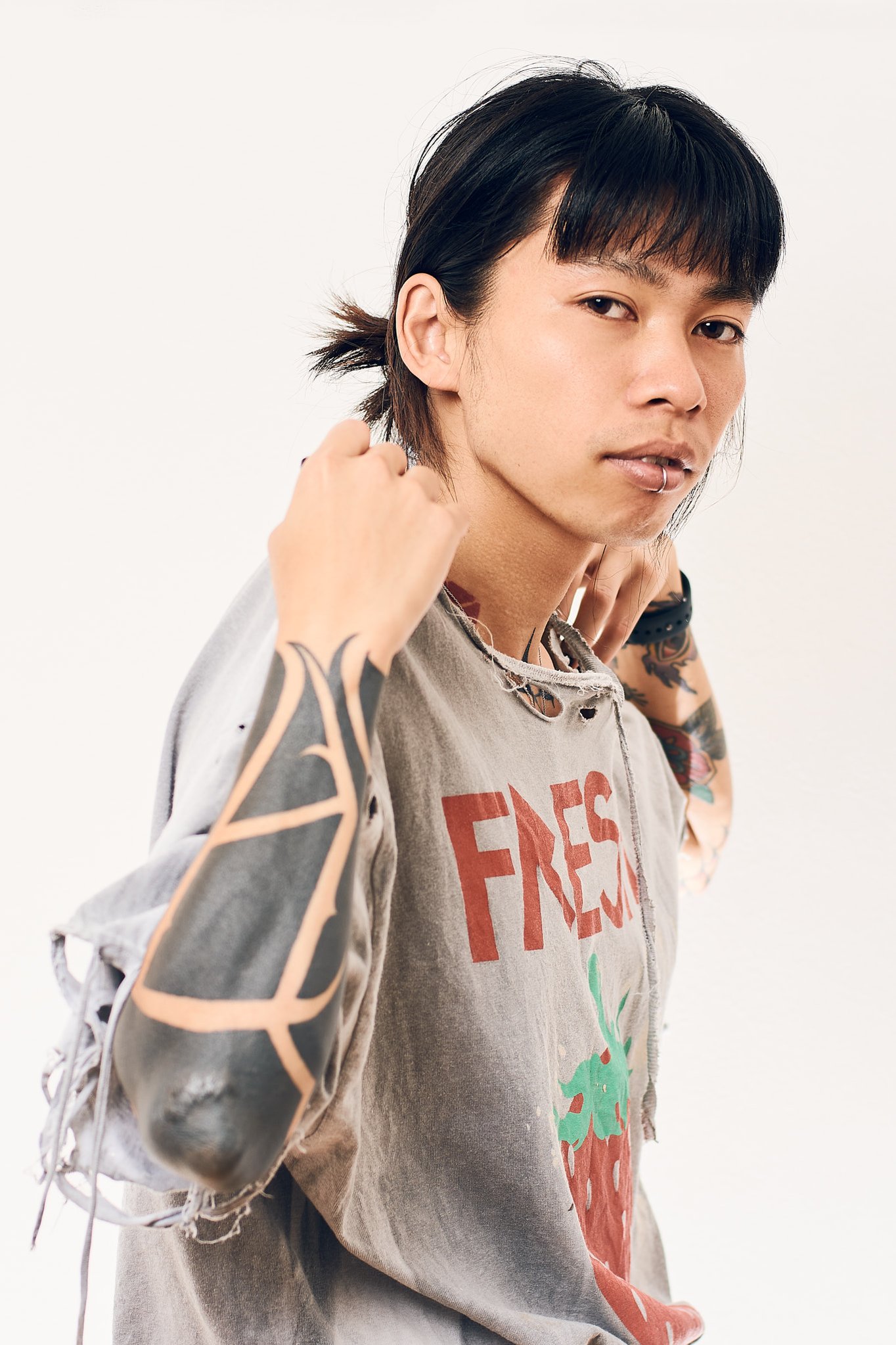 Portrait of a Japanese man with tattooed arms and his hands on his shoulders.